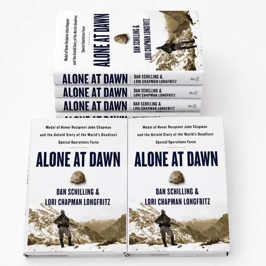 Multiple signed copies of Alone at Dawn by Dan Schilling and Lori Chapman Longfritz displayed in stack arrangement on white background